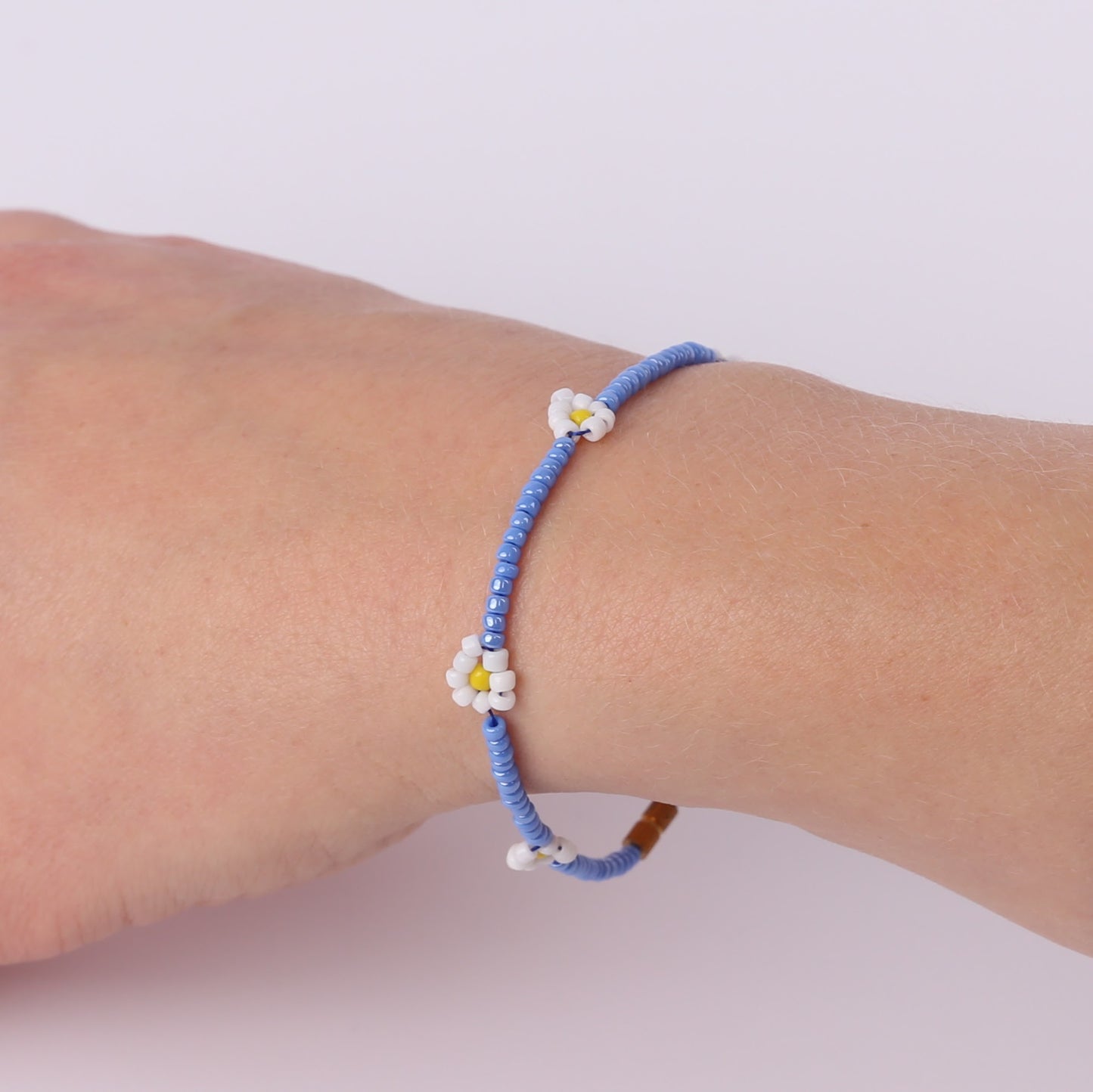 Pale blue beaded bracelet with white daisies on a wrist