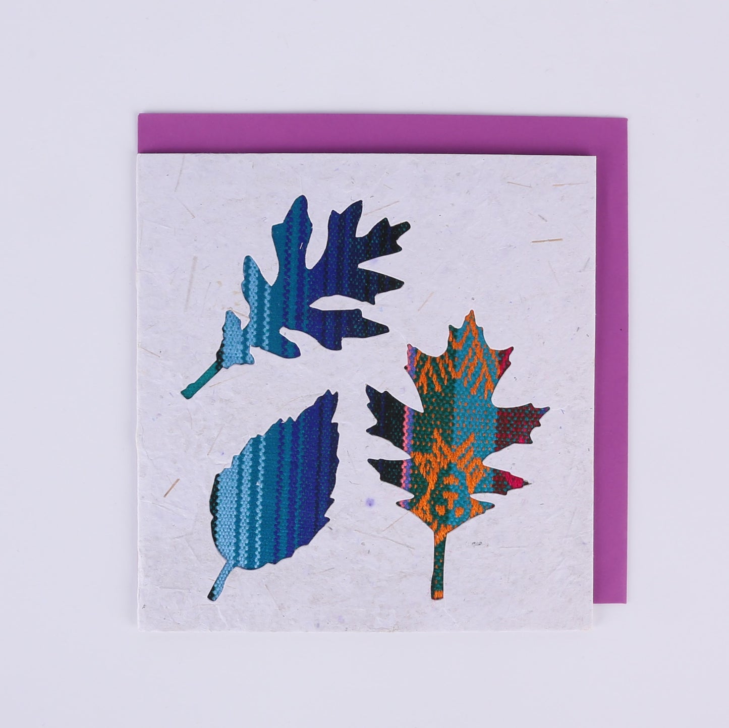 Colourful patterned leaf-shaped cutouts on a white square card with a purple envelope underneath