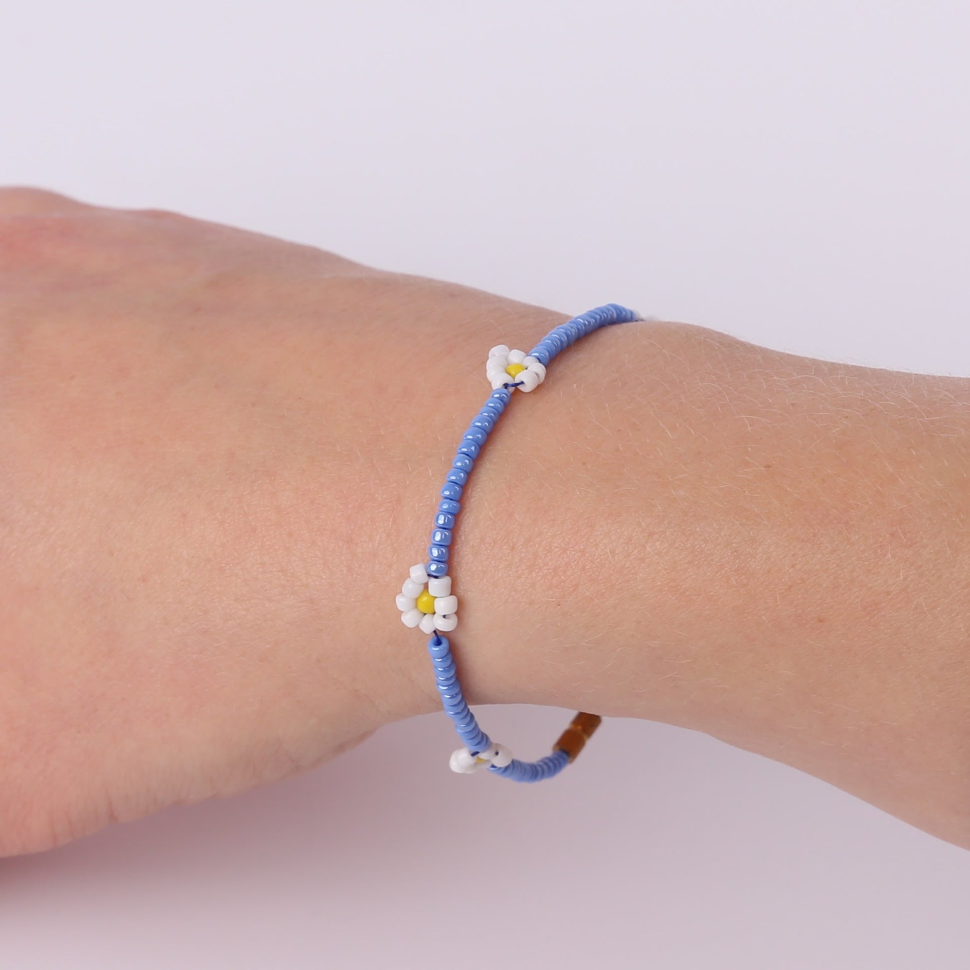 Pale blue beaded bracelet with white daisies on a wrist