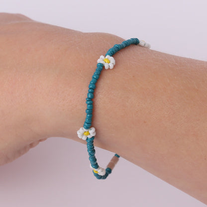 Teal beaded bracelet with white daisies on a wrist