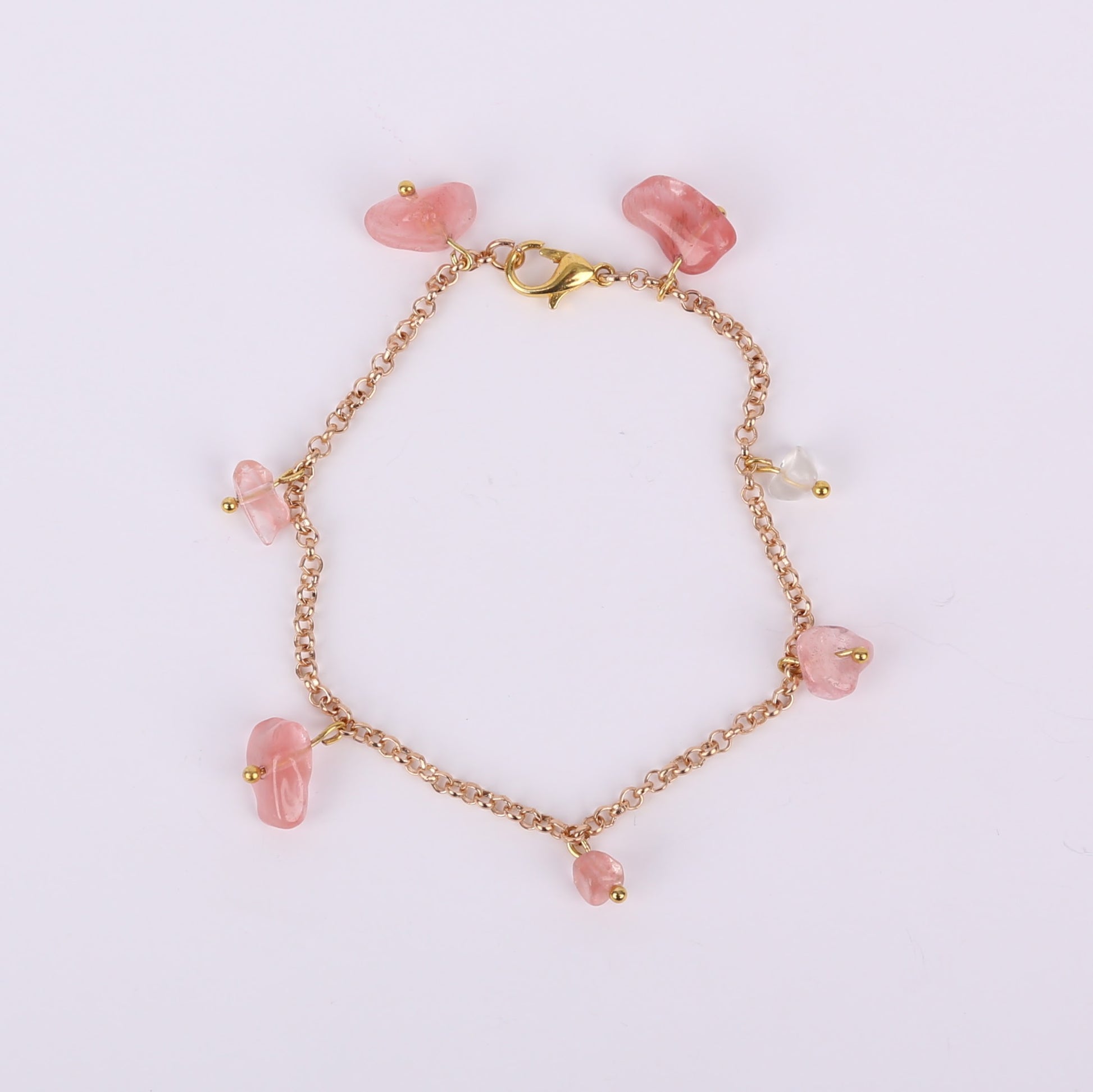 Gold bracelet with pink beads on a white background