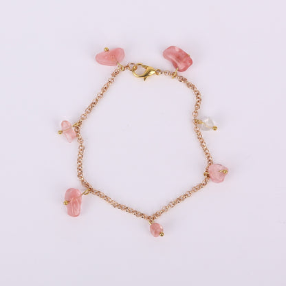 Gold bracelet with pink beads on a white background