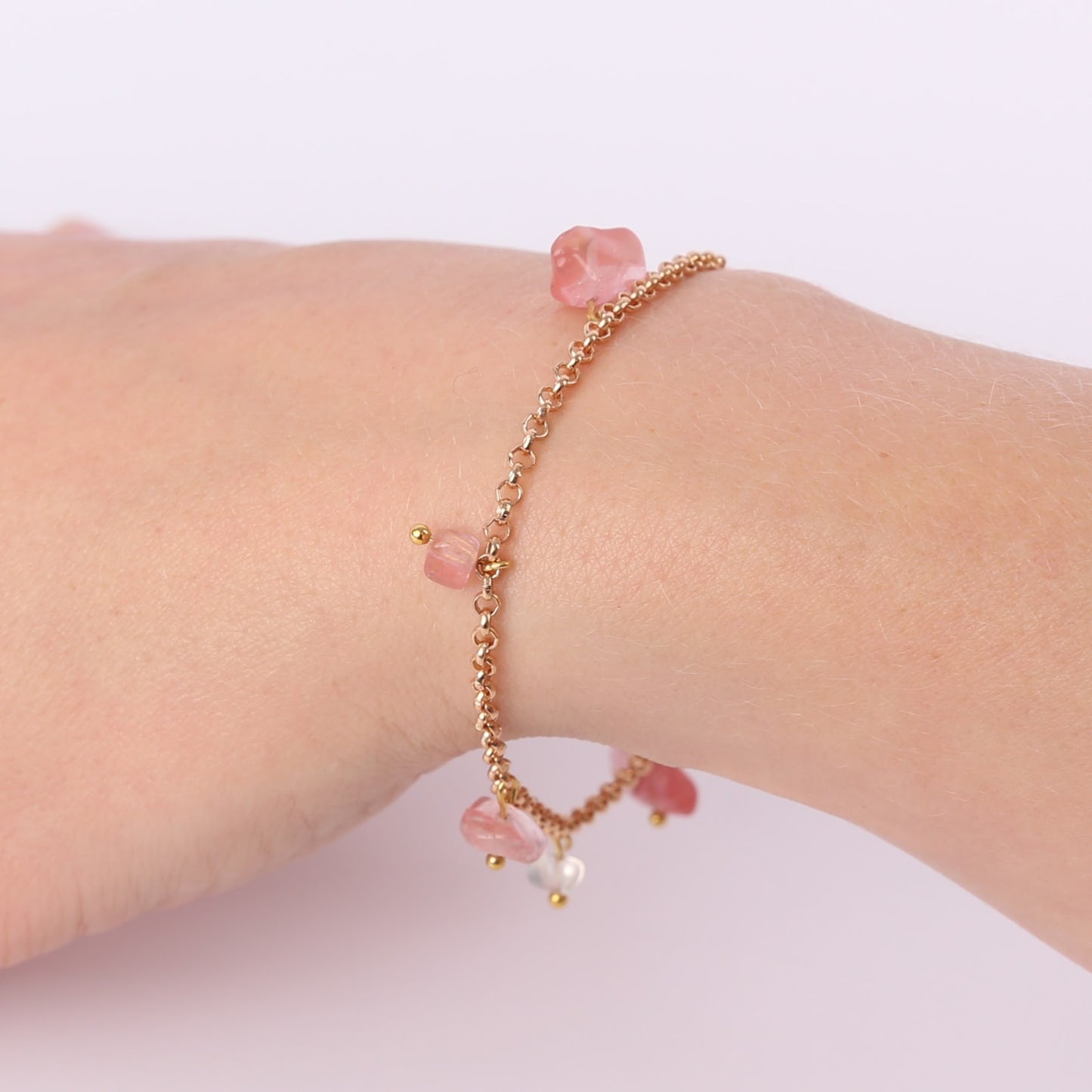 Gold bracelet with small pink stones on a wrist