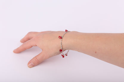 Silver bracelet with small red stones on a wrist