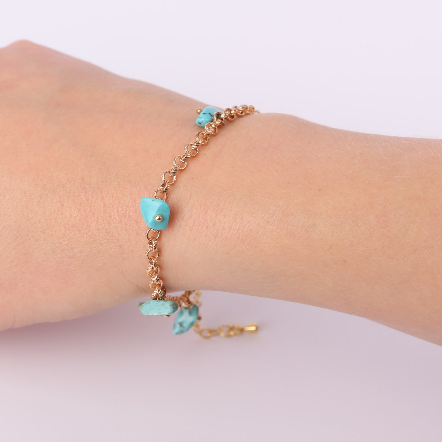Gold bracelet with small turquoise stones on a wrist