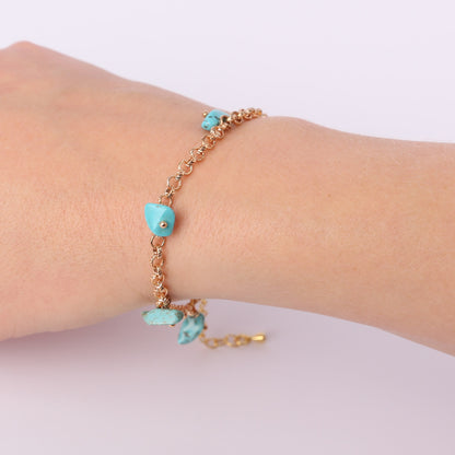 Gold bracelet with small turquoise stones on a wrist
