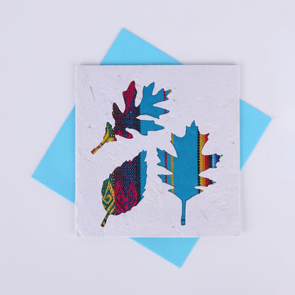 Colourful patterned leaf-shaped cutouts on a white square card with a blue envelope underneath