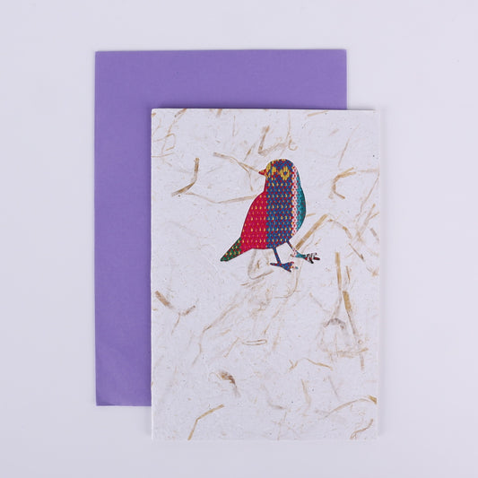 Colourful patterned bird cutout on a white card with a purple envelope underneath