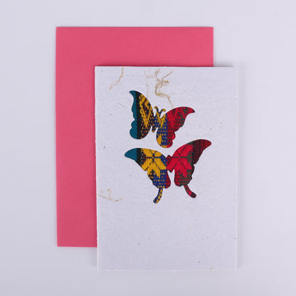 Colourful patterned butterfly cutouts on a white card with a pink envelope underneath