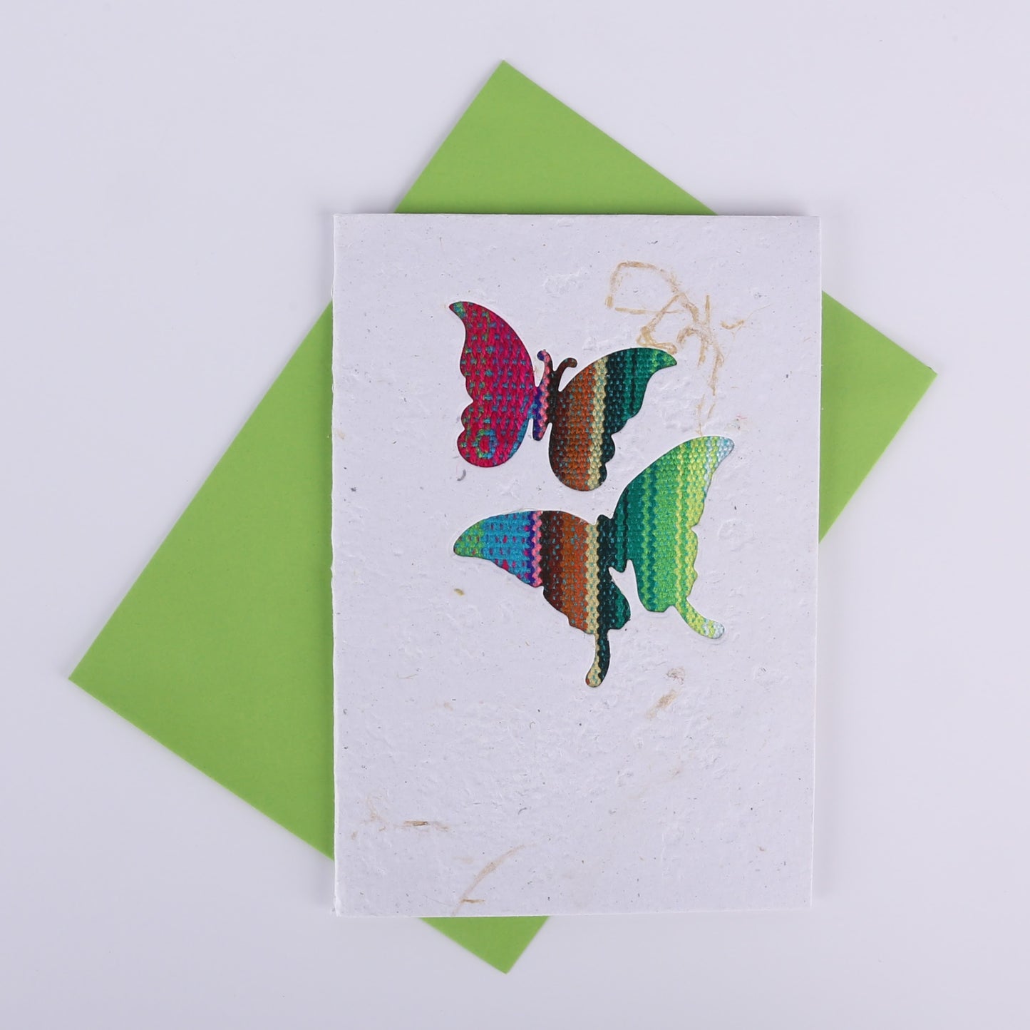 Colourful patterned butterfly cutouts on a white card with a green envelope underneath