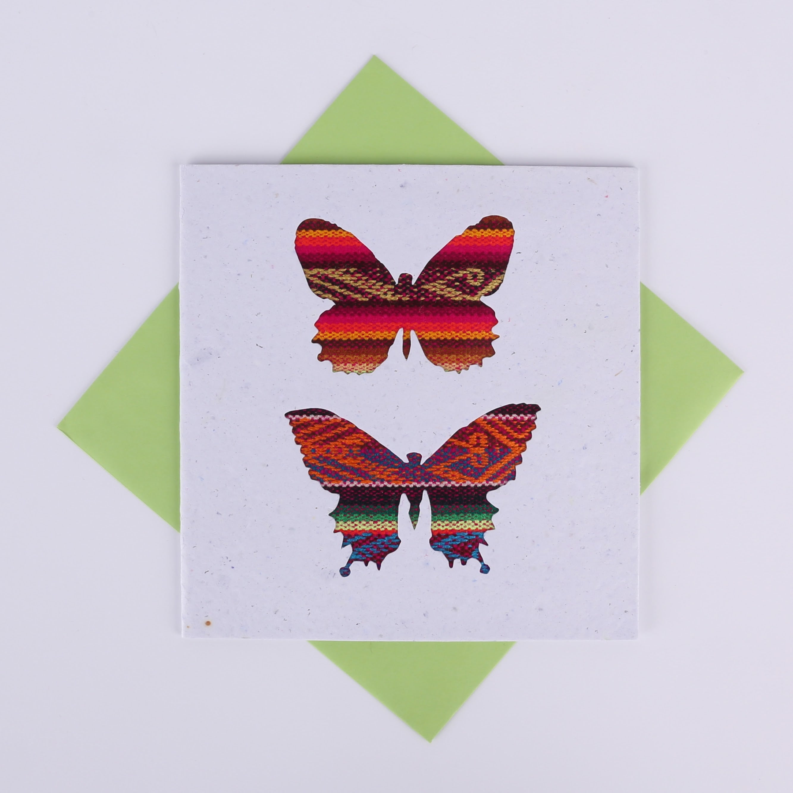 Colourful patterned butterfly cutouts on a white card with a green envelope underneath