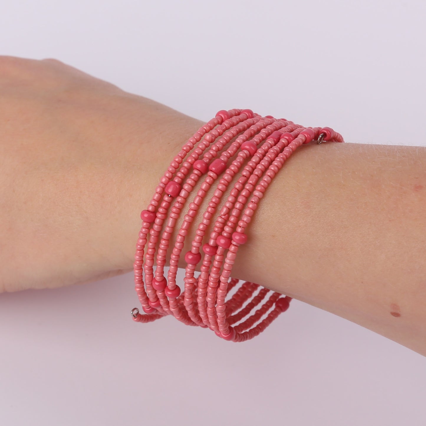 Coral coloured beaded spiral bracelet on a wrist